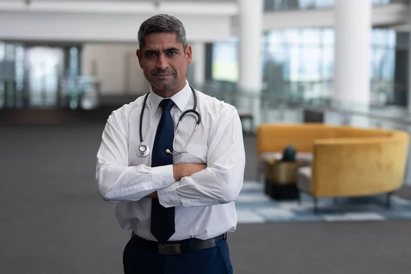 腕を組んで診療所でカメラ立って見て成熟した白人男性医師の肖像画 — ストック写真