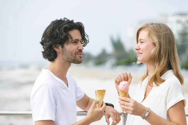 愉快的年轻白种人夫妇站在长廊 同时有冰淇淋蛋筒的侧视图 他们在微笑 — 图库照片