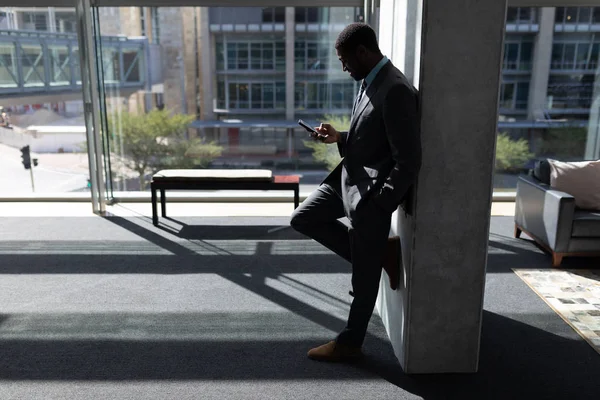 Vista Lateral Jovem Empresário Afro Americano Encostado Parede Usando Telefone — Fotografia de Stock