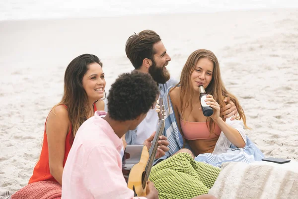 アフリカ系アメリカ人の友人女性がビールを飲みながらビーチで楽しんでいる間ギターのフロント ビュー — ストック写真