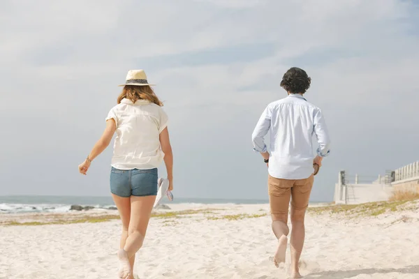 在阳光明媚的日子里 在海滩上奔跑的年轻白人夫妇的后景 — 图库照片