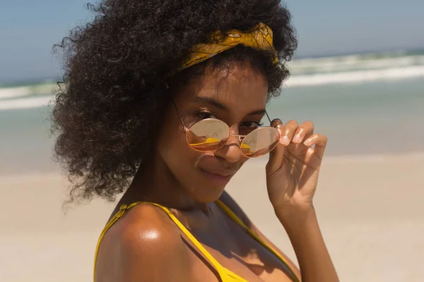ビキニを着てビーチでサングラスを見ている若いアフリカ系アメリカ人女性の肖像画 — ストック写真
