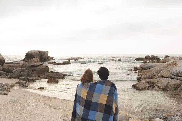 Vista Trasera Joven Pareja Caucásica Envuelta Manta Pie Playa Están —  Fotos de Stock