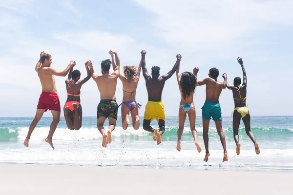 Rear View Different Group Friends Jusing Jumping Water Beach Sunny — стоковое фото