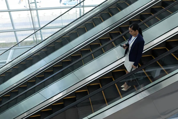 Mischlingsunternehmerin Benutzt Handy Während Sie Auf Rolltreppe Büro Herunterfährt — Stockfoto