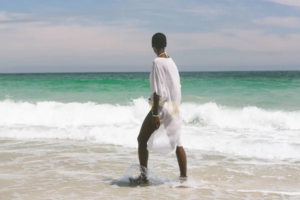 晴れた日にビーチでリラックスして歩くアフリカ系アメリカ人女性の背面図 — ストック写真