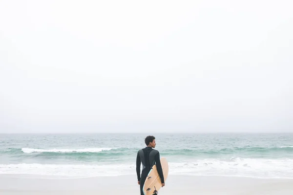Задний Вид Вдумчивого Молодого Сёрфера Смешанной Расы Держащего Доску Сёрфинга — стоковое фото