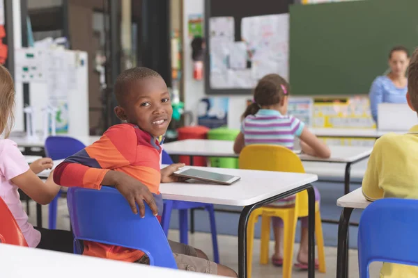 Bakifrån Lycklig Afrikansk Skolpojke Innehar Digital Tablet Vid Skriv Bordet — Stockfoto