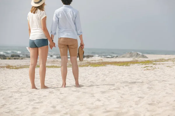 Visão Traseira Jovem Casal Caucasiano Mãos Dadas Praia Com Calçado — Fotografia de Stock