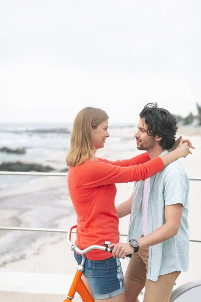 在海滩上骑自行车时 浪漫的年轻高加索夫妇的侧视图使对方尴尬 他们在微笑 — 图库照片