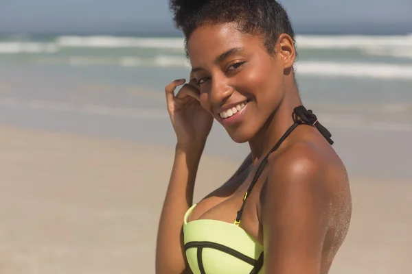 緑ビキニを着てビーチにカメラを見て幸せな若いアフリカ系アメリカ人女性の肖像画 彼女は笑顔とカメラ目線 — ストック写真