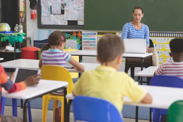 Widok Przodu Nauczyciela Przy Użyciu Laptopa Klasie Podczas Gdy Dzieci — Zdjęcie stockowe