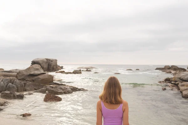 ビーチに立っている若い白人金髪女性の背面 彼女は海を見ています — ストック写真