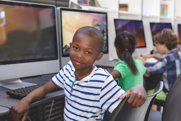 コンピュータの上に椅子に座って コンピュータ室のカメラを見て幸せなアフリカ系アメリカ人の男子生徒の肖像 — ストック写真