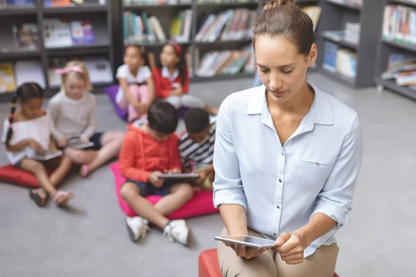 Overhead Bekijken Van Leraar Zoek Naar Haar Tablet Terwijl Schoolkinderen — Stockfoto