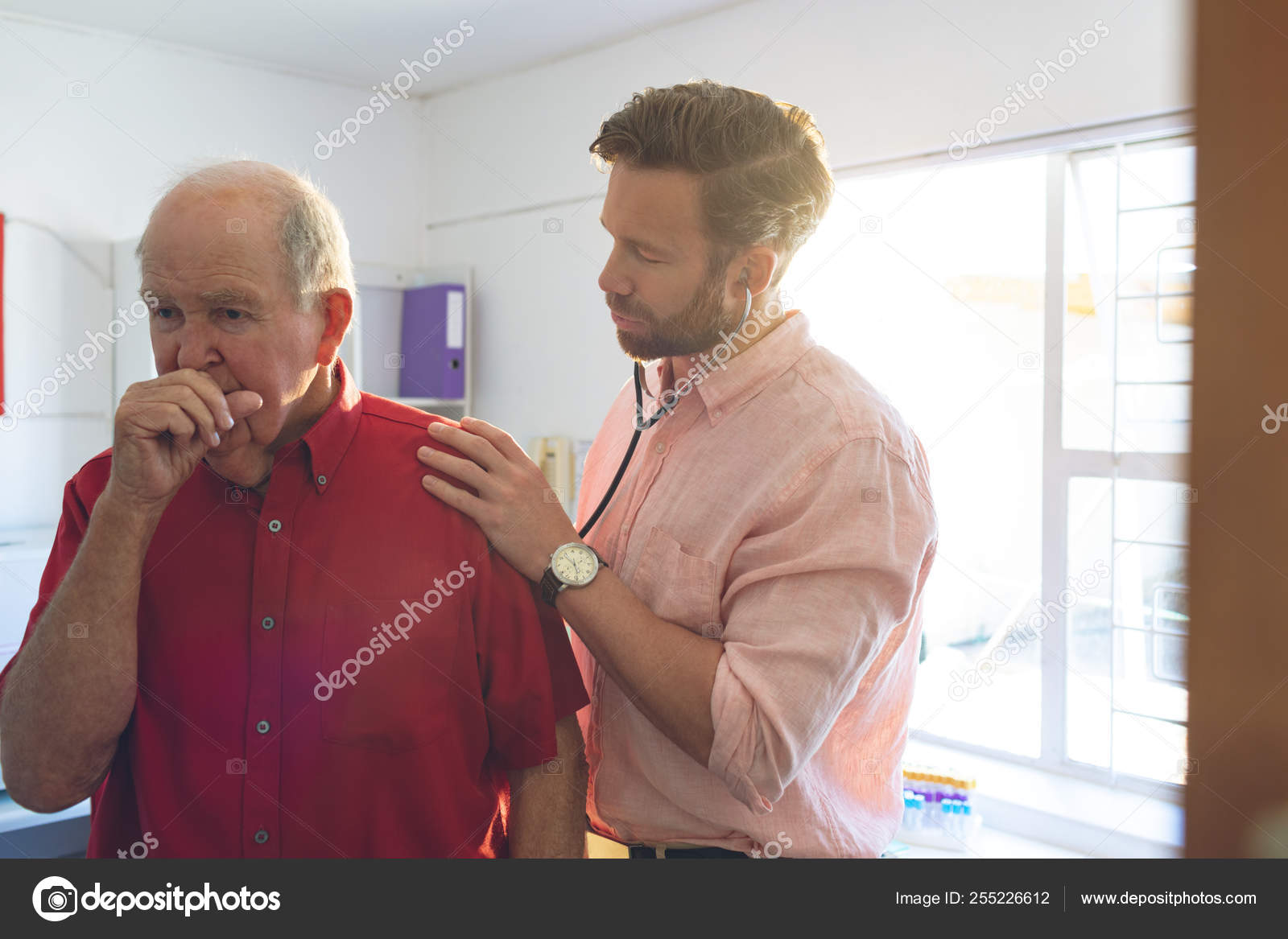一位白人男性医生在咳嗽时使用听诊器检查一名老年病人的正面看法 图库照片 C Wavebreakmedia