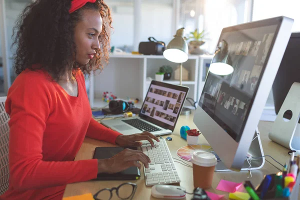 若いミックスレース女性グラフィックデザイナーのサイドビューモダンオフィスのデスクでデスクトップ を操作する — ストック写真
