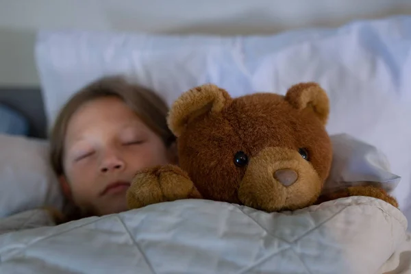在医院里与泰迪熊睡在床上的高加索女孩的正面看法 — 图库照片
