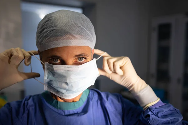 Vista Frontal Uma Cirurgiã Branca Olhando Para Câmera Enquanto Colocava — Fotografia de Stock
