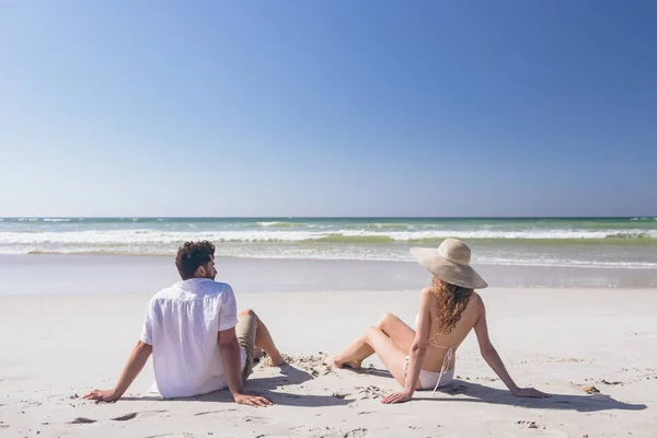 在阳光明媚的日子里 年轻的高加索夫妇坐在沙滩上放松的后景 他们在寻找海洋 — 图库照片
