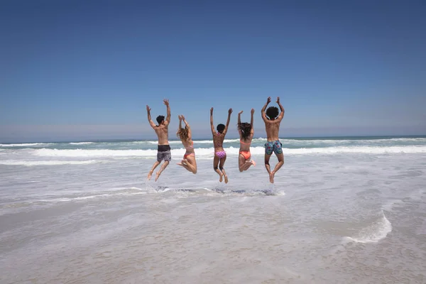 Вид Счастливую Группу Друзей Разных Национальностей Прыгающих Вместе Пляже Лучами — стоковое фото