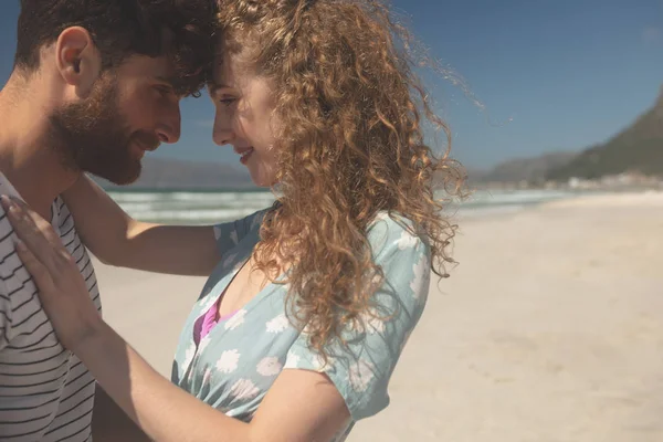 晴れた日にビーチでロマンチックな白人カップルに立っての側面図です 彼らはお互いを抱いています — ストック写真