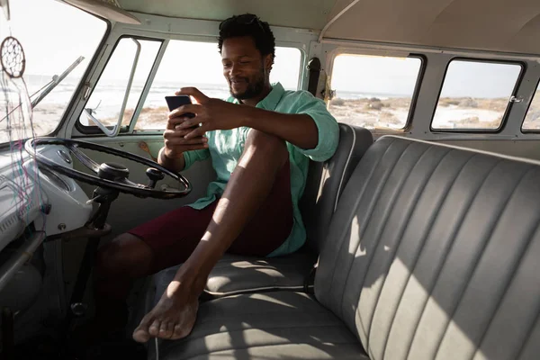 Vista Frontal Hombre Africano Sentado Una Caravana Mientras Usa Teléfono —  Fotos de Stock