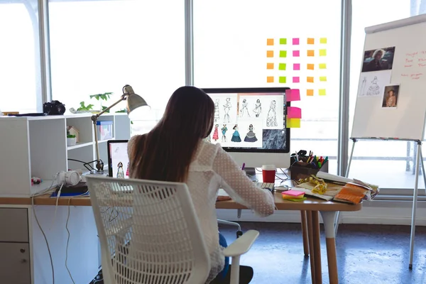 年轻的高加索女性时装设计师在现代办公室的办公桌上工作的后景 — 图库照片