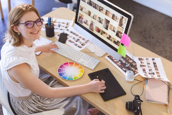 若い白人女性グラフィックデザイナーの肖像オフィスのデスクでグラフィックタブレットで作業しています 彼女は微笑んでいて カメラを見ている — ストック写真