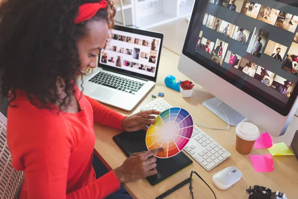 年轻的混血女平面设计师在现代办公室的办公桌上使用色板的高角度视角 — 图库照片