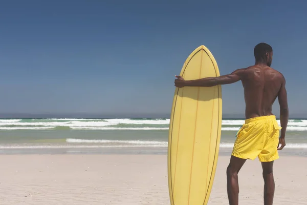 晴れた日にビーチでサーフボードの立っているとアフリカ系アメリカ人の男性サーファーの後姿 — ストック写真