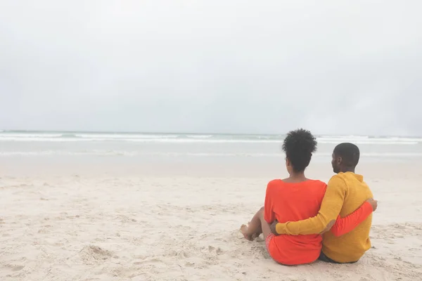 ビーチで海を見ながらリラックスロマンチックなマルチエスニックカップルの背面図 — ストック写真