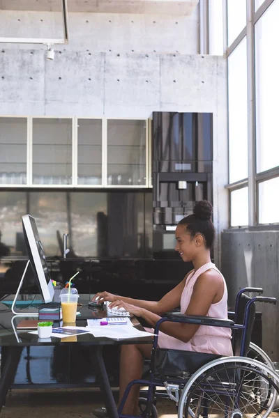 年轻残疾混血女商人在现代办公室办公桌上工作的侧视图 — 图库照片