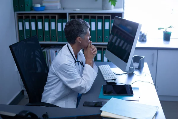 Visão Lateral Uma Médica Branca Pensativa Olhando Para Computador Enquanto — Fotografia de Stock