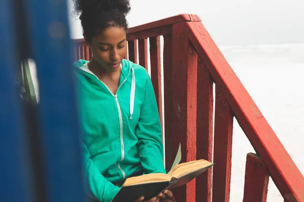 Vista Frontal Hermosa Joven Mujer Raza Mixta Leyendo Libro Mientras —  Fotos de Stock