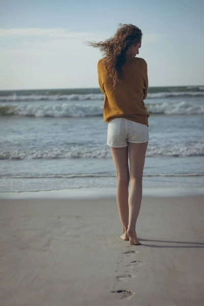 晴れた日にビーチで砂の上を歩いての若い白人女性の後姿 — ストック写真