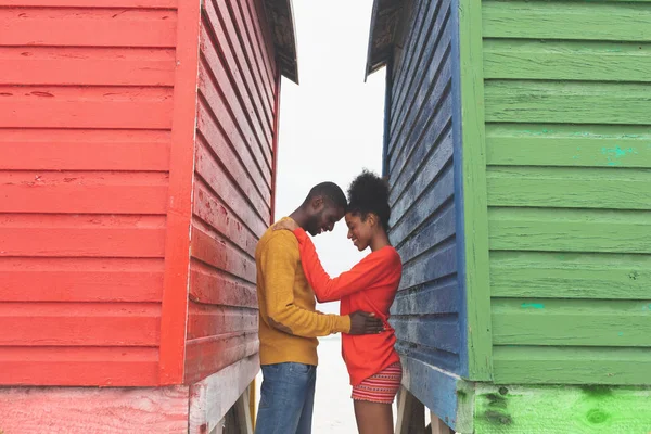 ビーチ小屋の間で互いに抱き合うロマンチックなマルチエスニックカップルの側面図 カップルはお互いに触れ合う — ストック写真