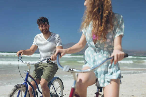 在阳光明媚的日子里 在海滩上骑自行车 同时彼此互动 可以欣赏到年轻的高加索夫妇的美景 他们在微笑 — 图库照片