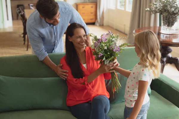自宅のリビングルームで母親に花束を与える白人の娘の側面図 — ストック写真