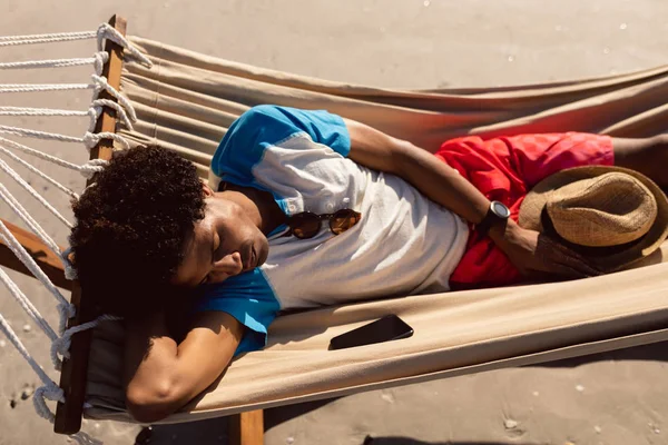 ビーチのハンモックで眠るアフリカ系アメリカ人の若者の高い角度の眺め — ストック写真