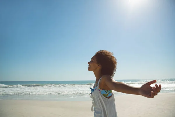 非洲裔美国妇女站在沙滩上伸出双臂的侧视图 — 图库照片