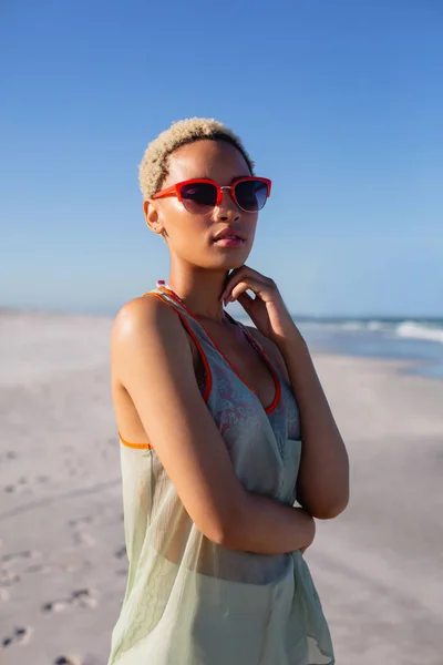 太陽の下でビーチでカメラを見てサングラスをかけた美しいアフリカ系アメリカ人女性の正面図 — ストック写真