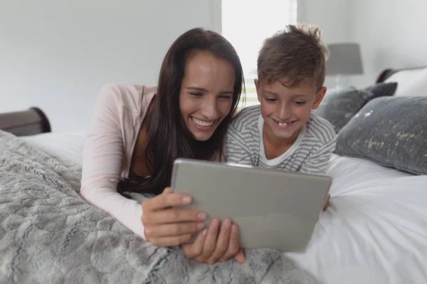 自宅の寝室でデジタルタブレットを使用して幸せな白人の母と息子の正面図 — ストック写真