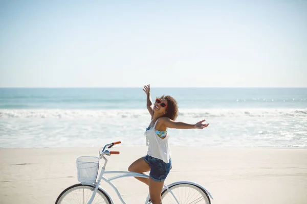 美丽的非洲裔美国妇女骑自行车的侧视图 手臂伸出在海滩上 — 图库照片