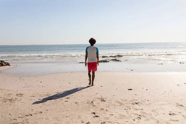 晴れた日にビーチを歩くアフリカ系アメリカ人男性の背面図 — ストック写真