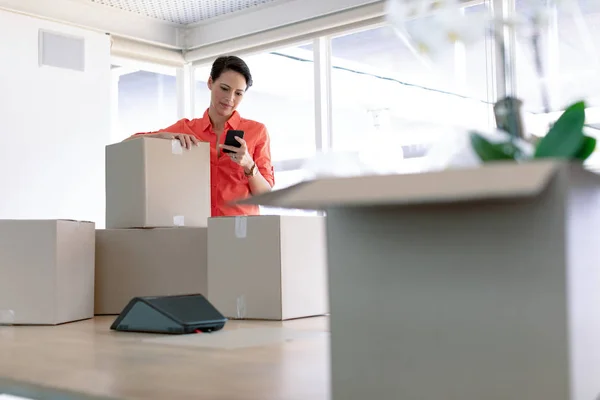 새로운 사무실에서 전화를 사용하여 골판지 상자와 아름다운 사업가의 측면보기 — 스톡 사진