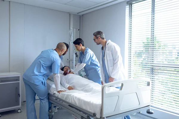 医院病房病房里 不同医生在病床上检查亚洲女病人的侧视图 病人戴着氧气面罩 — 图库照片