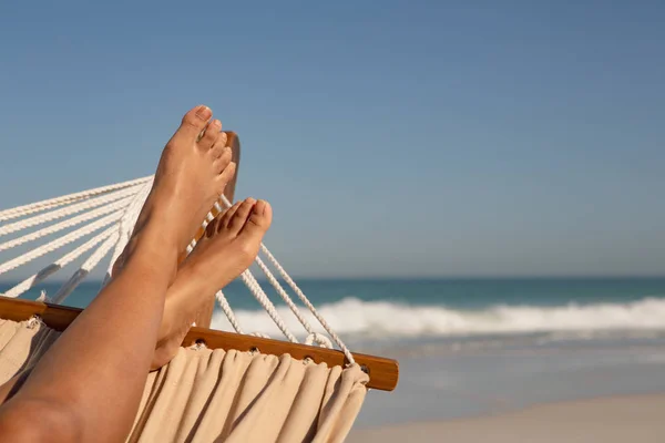 日差しの中でビーチでハンモックでリラックスする女性の低いセクション — ストック写真