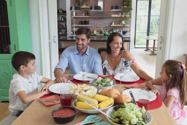 快適な家のダイニングテーブルで互いに相互作用する幸せな白人家族の正面図 — ストック写真