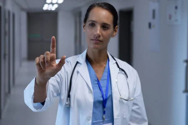 白人女医生假装在医院走廊里触摸隐形屏幕的正面视图 — 图库照片